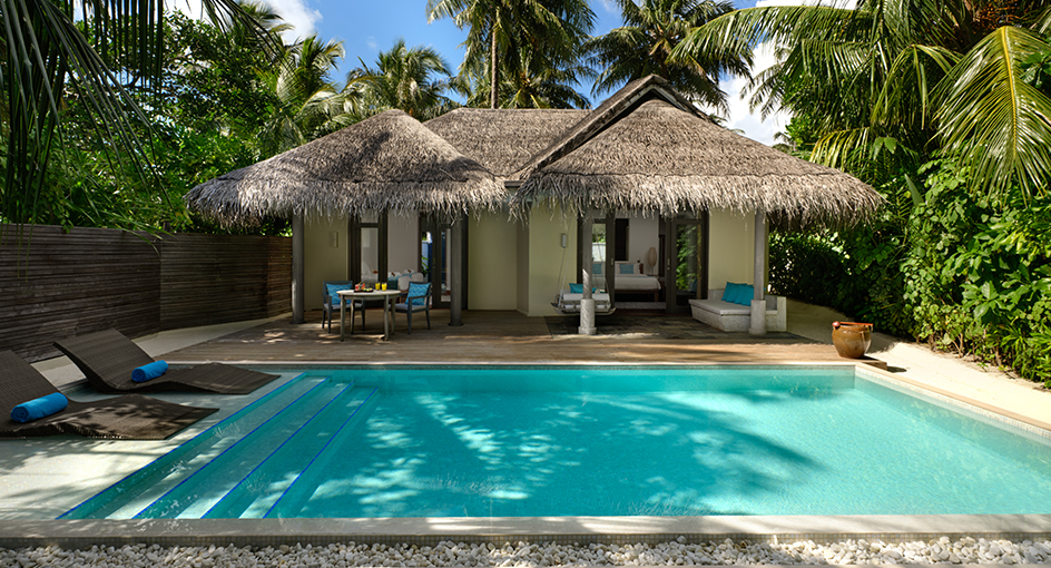 Private villa with thatched roof, turquoise pool, loungers, and dining area surrounded by palm trees at Anantara Dhigu Maldives Resort.