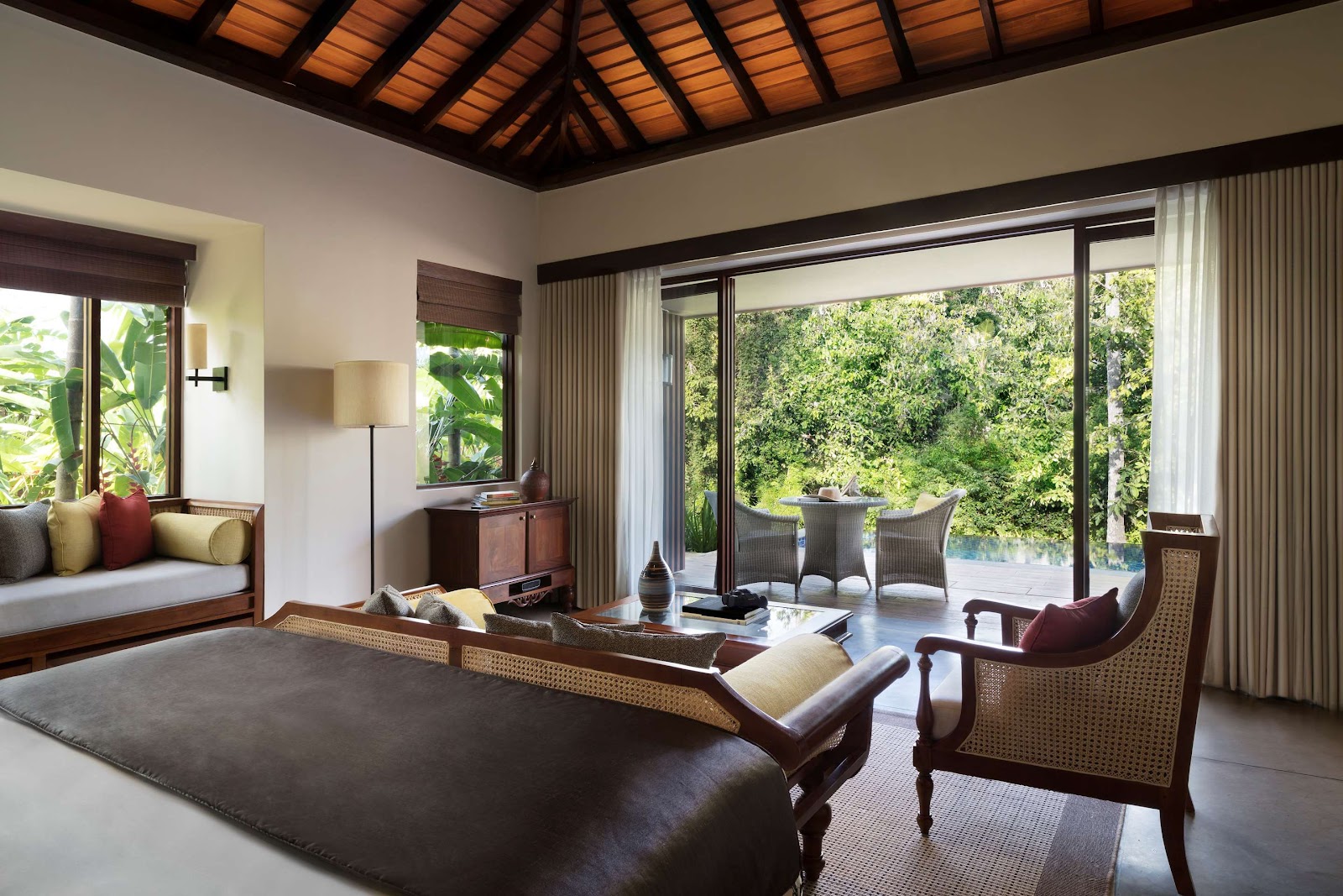Spacious villa interior with wooden ceiling, modern furnishings, and large glass doors opening to a garden terrace at Anantara Peace Haven Tangalle Resort.