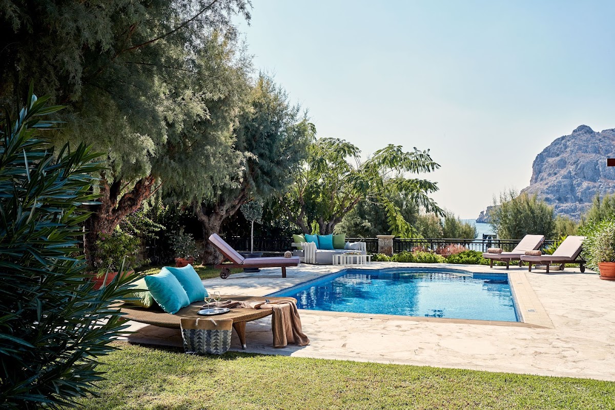 Pool surrounded by loungers and mature trees with mountain views at Atlantica Imperial Resort and Spa.