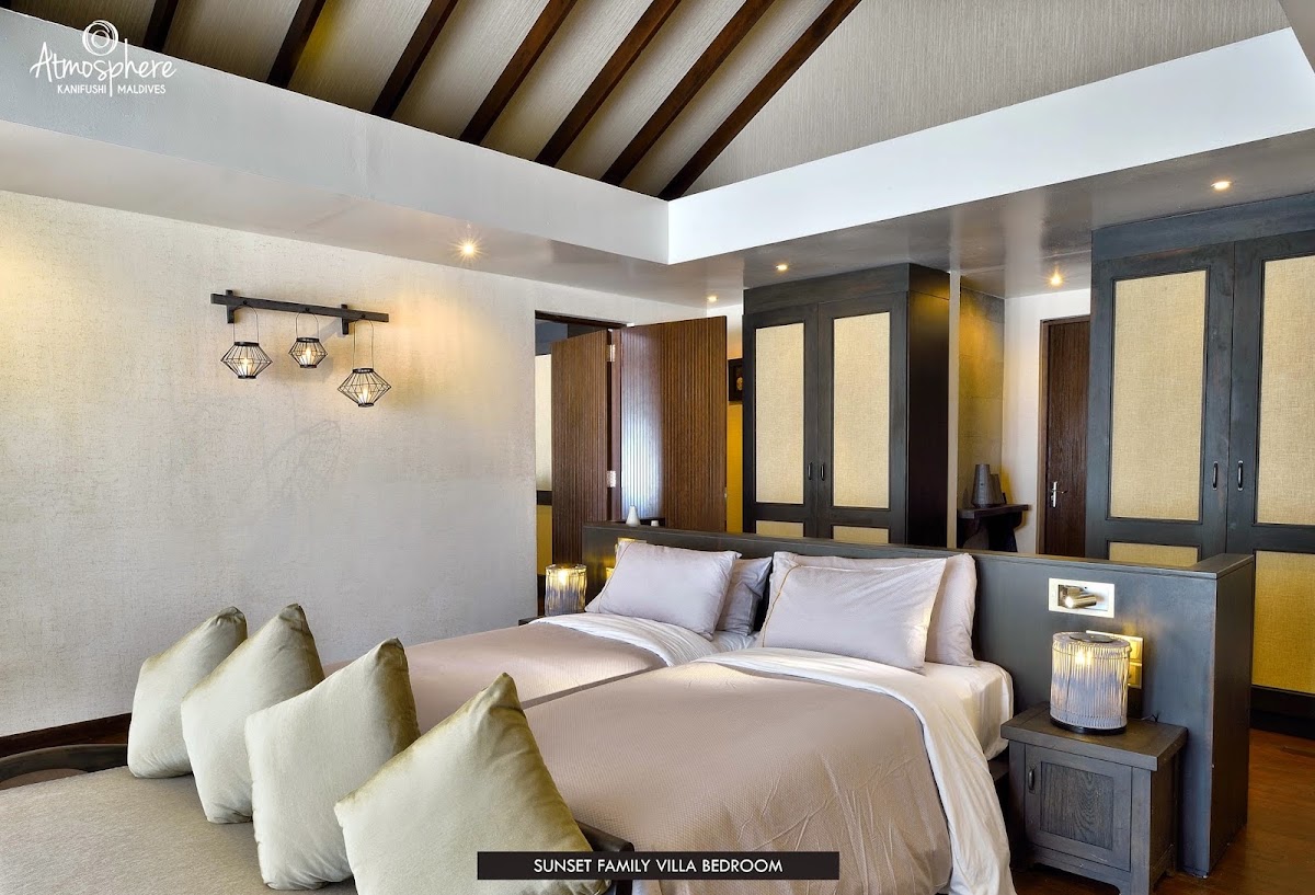 Sunset Family Villa bedroom at Atmosphere Kanifushi with king bed, cream pillows, dark wood cabinetry, and skylight ceiling.