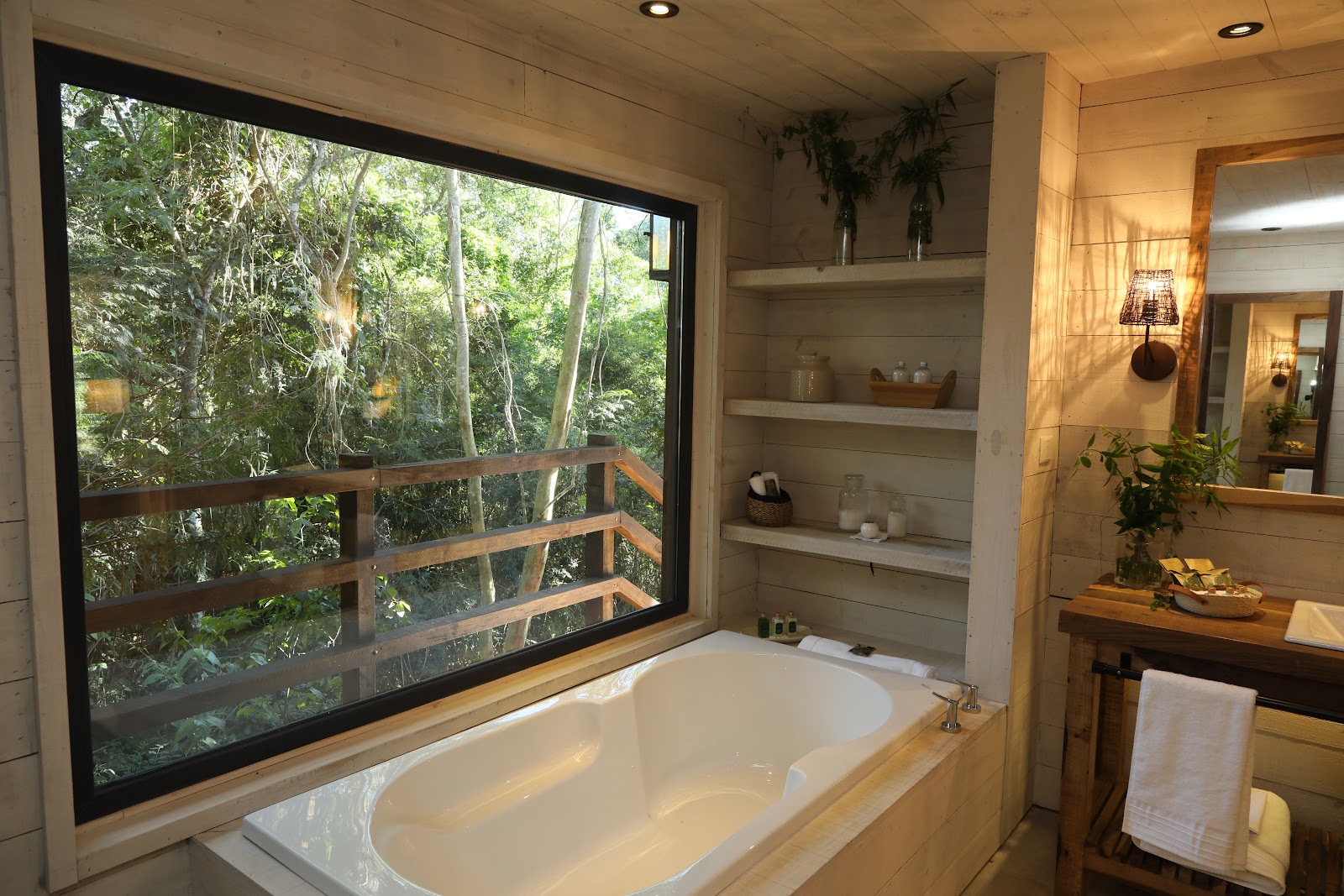 Bathroom with soaking tub facing large window overlooking dense jungle canopy at Awasi Iguazú.