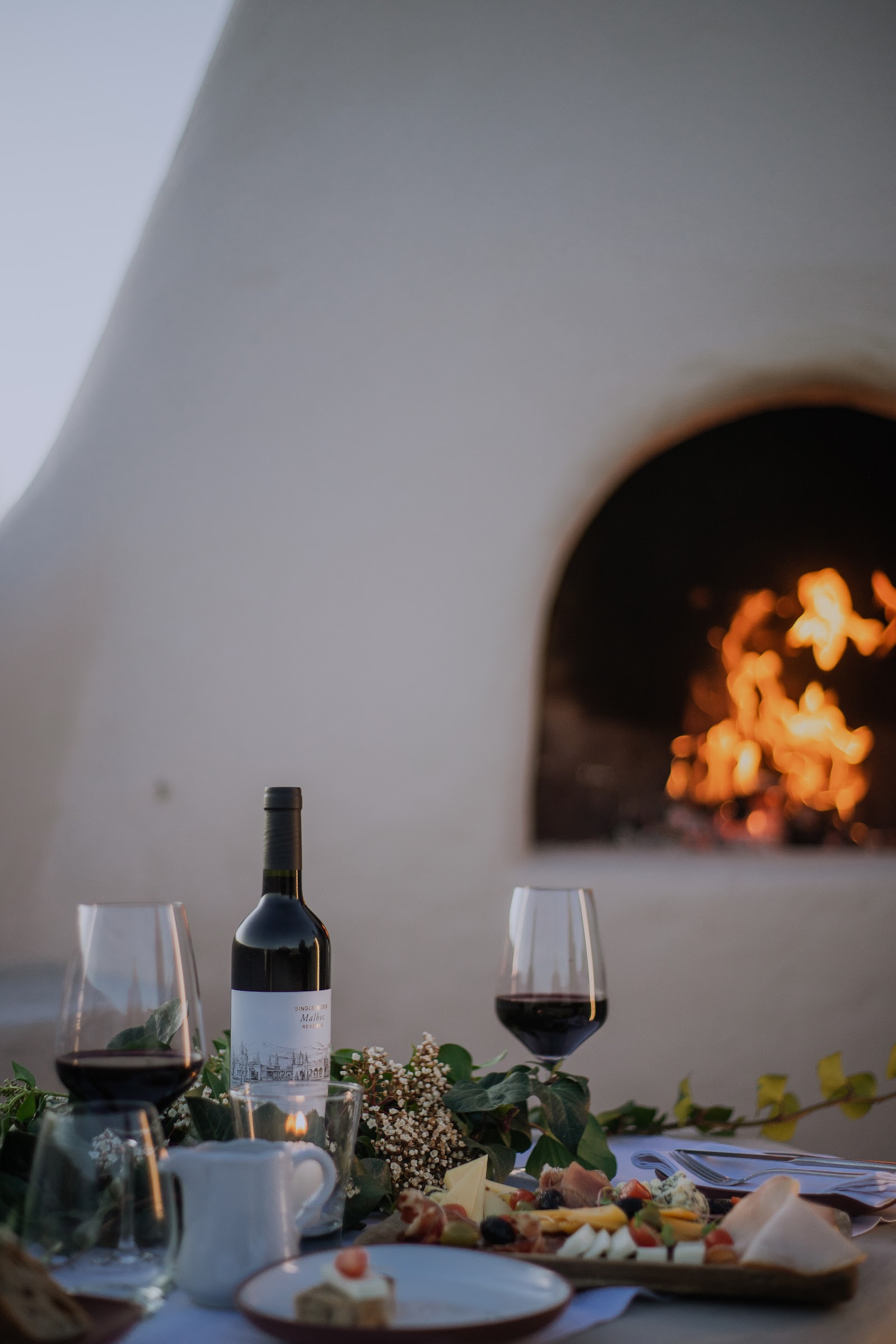 Two glasses of red wine and plated dishes with roasted yellow pepper, asparagus, and greens at a fine dining table.