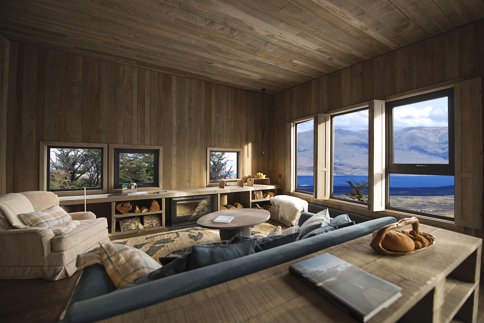 Wood-paneled lounge with large windows framing mountain and lake views at Awasi Patagonia in Chile.