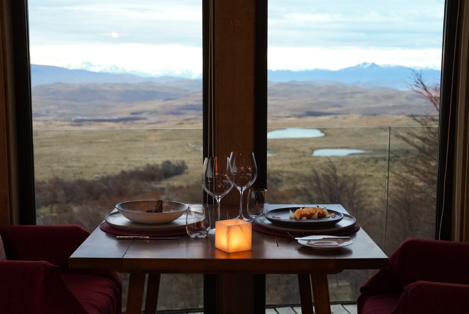 Wooden deck with fire pit overlooking Patagonian valley, mountains, and lake at Awasi Patagonia.