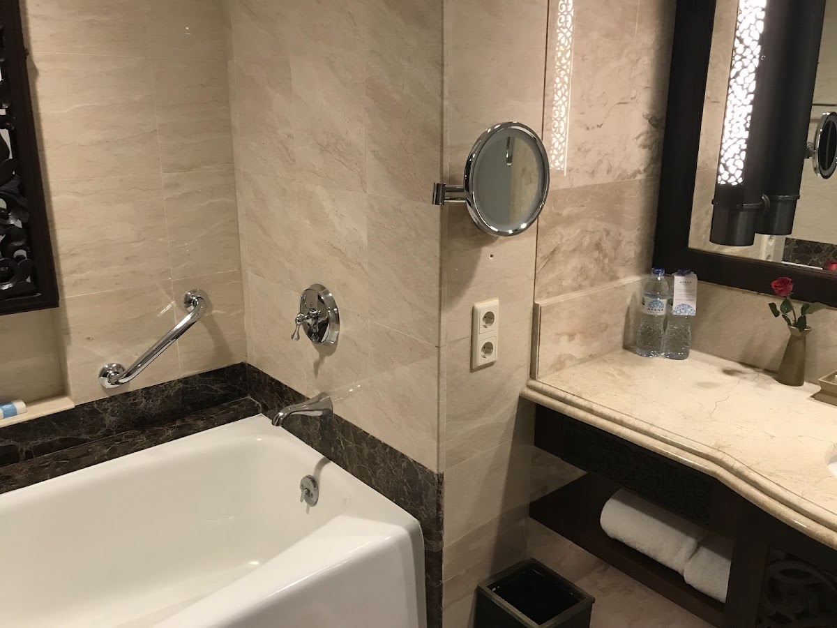 Marble bathroom with soaking tub, walk-in shower, dual vanities, and amenities at AYANA Resort Bali.