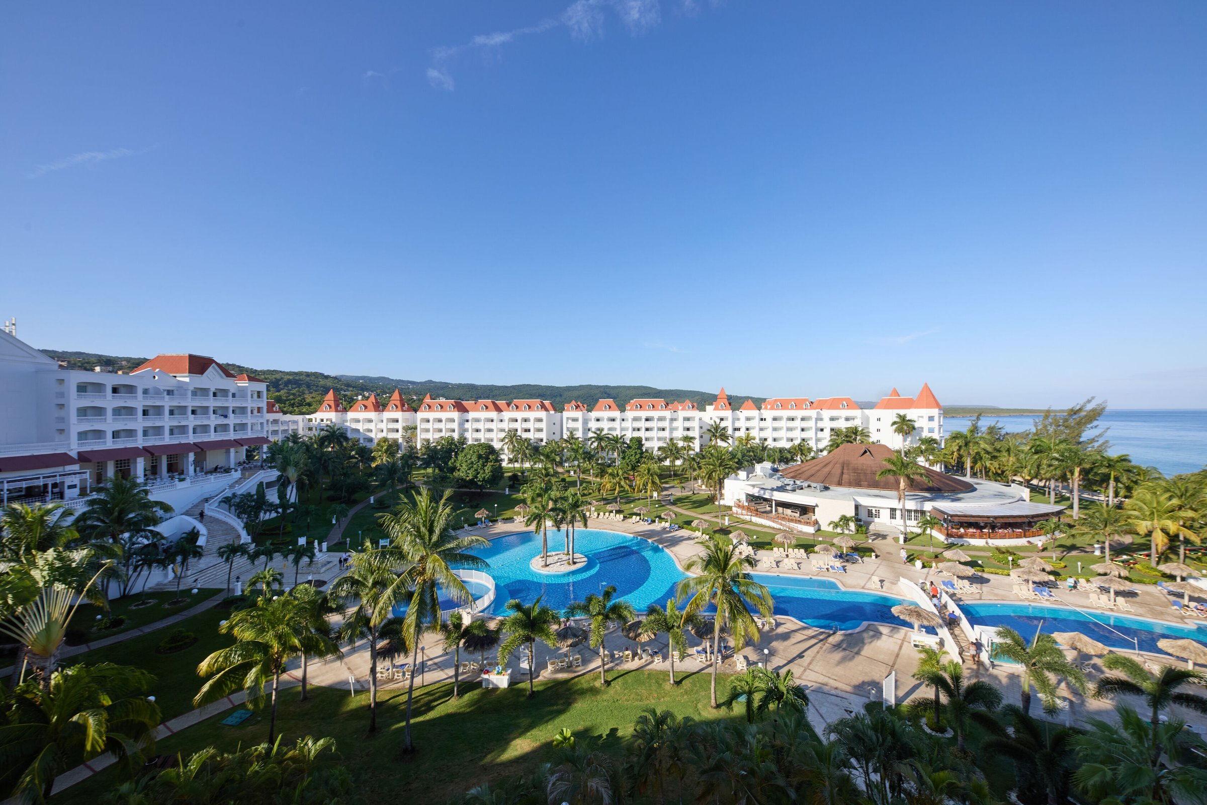 Aerial view of the resort buildings, winding pool and sea