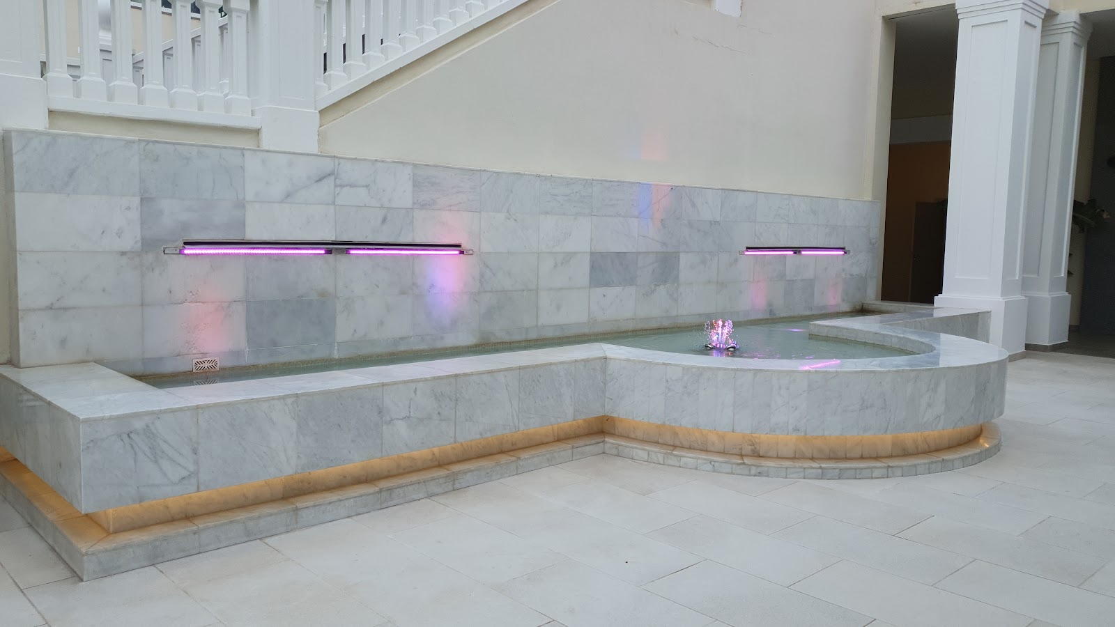 Indoor spa bathing area with marble-tiled soaking pools, purple accent lighting, and white columns at Bahia Principe Fantasia Tenerife.