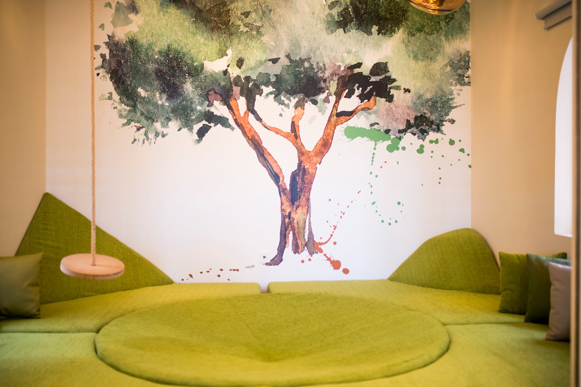 Kids club play nook with tree mural and swing