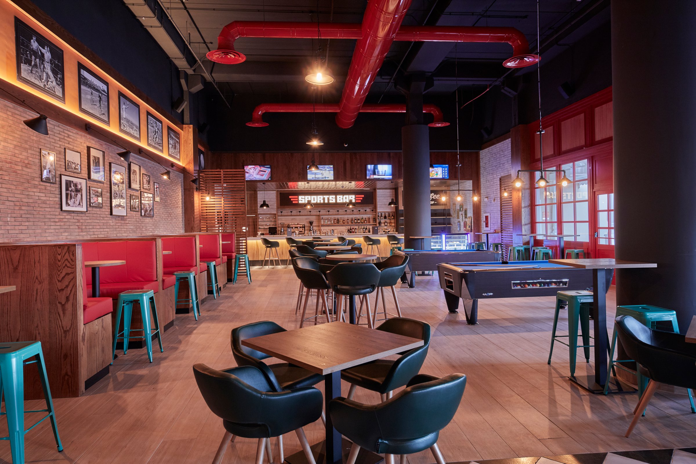 Sports bar with booths, pool table and exposed red pipes