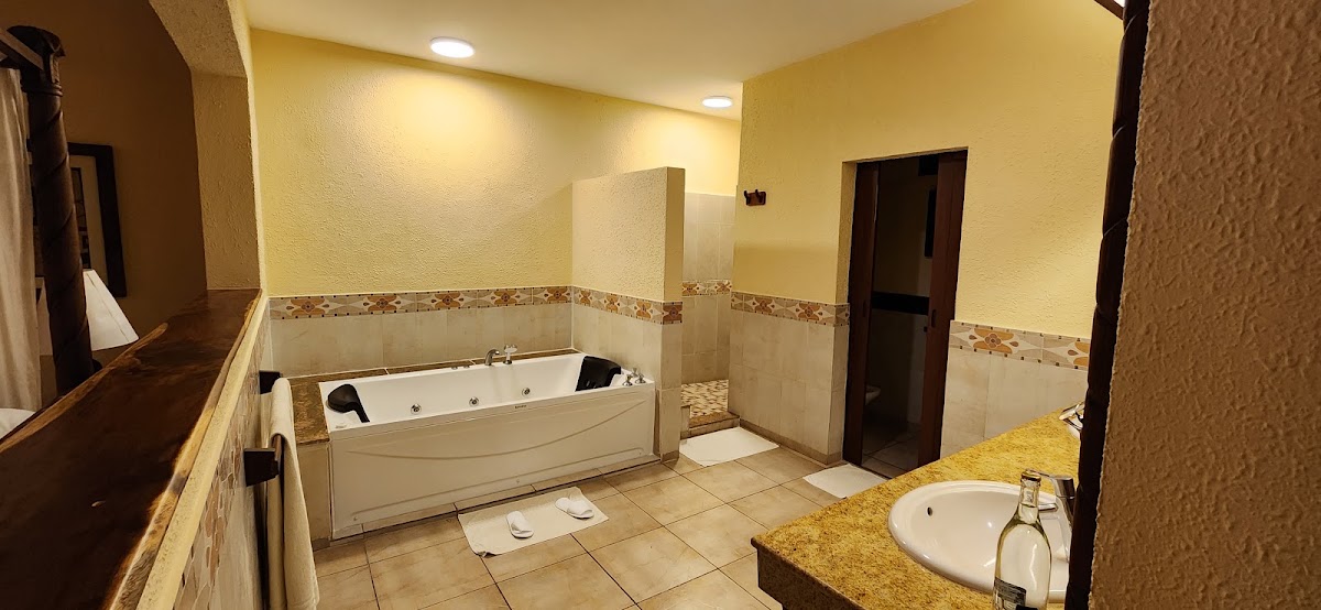 Spacious bathroom with yellow walls, jet tub, separate shower enclosure, and granite vanity with round sink.