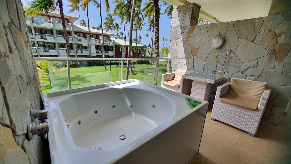 Outdoor whirlpool tub on a stone patio at Barceló Bávaro Palace, with resort buildings and manicured lawn visible beyond the railing.