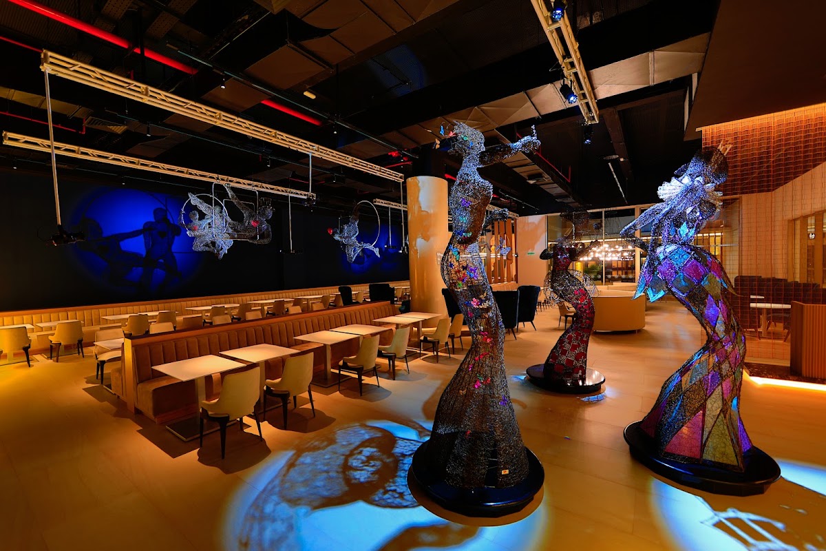 Barceló Maya Riviera nightclub interior with glittering sculptural figures, booth seating, and blue uplighting.