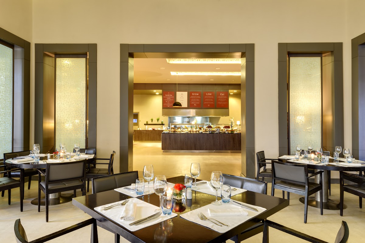 Modern resort dining room with black tables, white place settings, and open kitchen visible through central archway.
