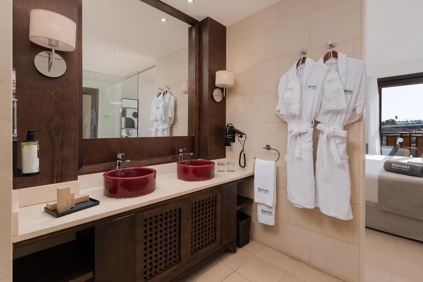 Soaking tub with jets and mirror reflecting a suite's living area with cream sofa and ocean view at Barceló Tenerife.