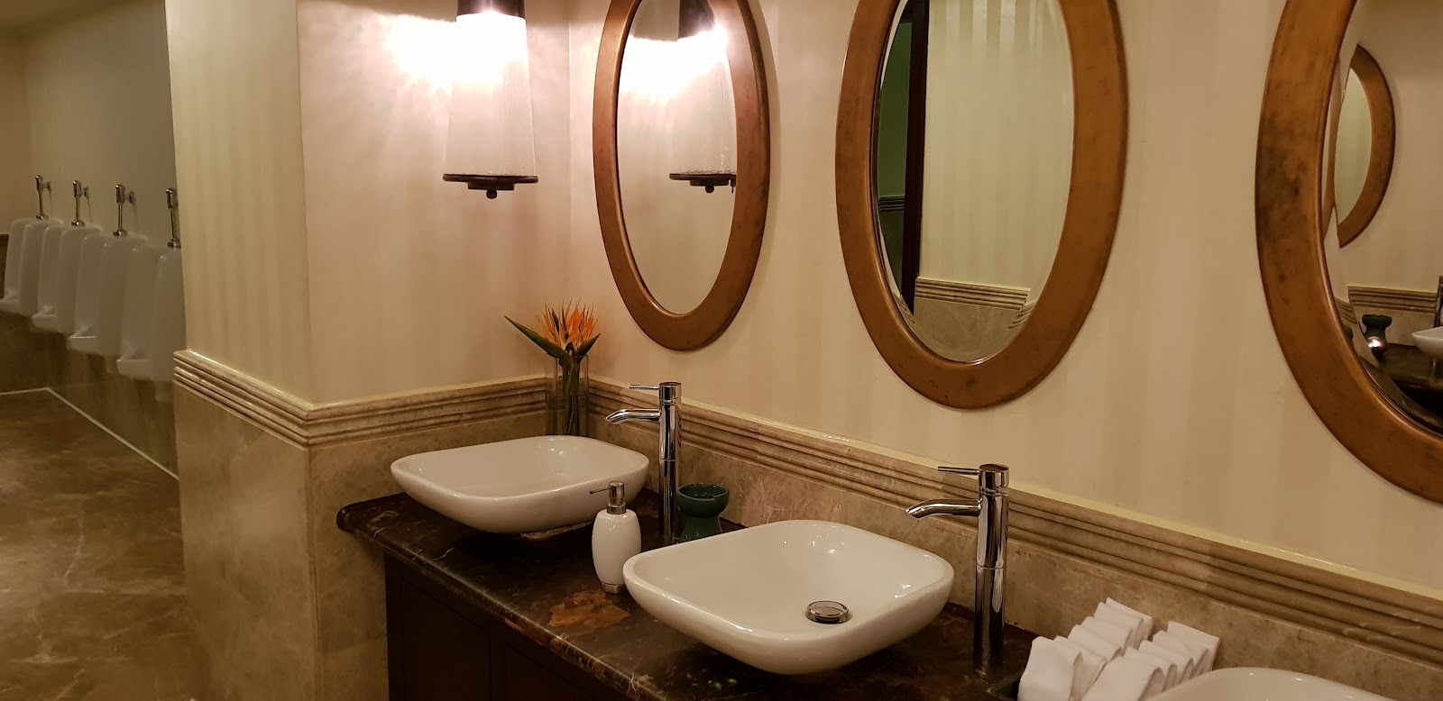 Bathroom vanity with two white vessel sinks, wood-framed round mirrors, and sconces at Baron Palace Sahl Hasheesh.