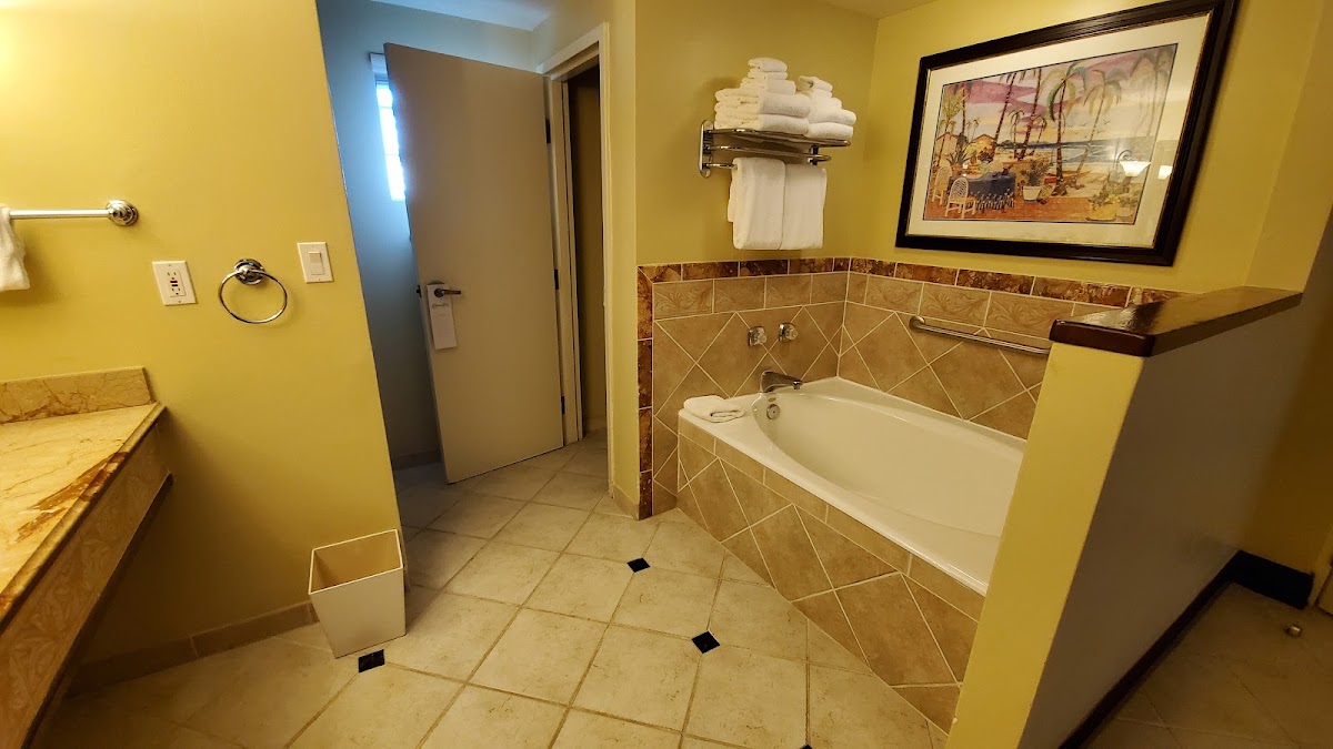 Bright yellow bathroom with tile flooring, soaking tub with brown surround, and towel rack at Beaches Turks & Caicos.