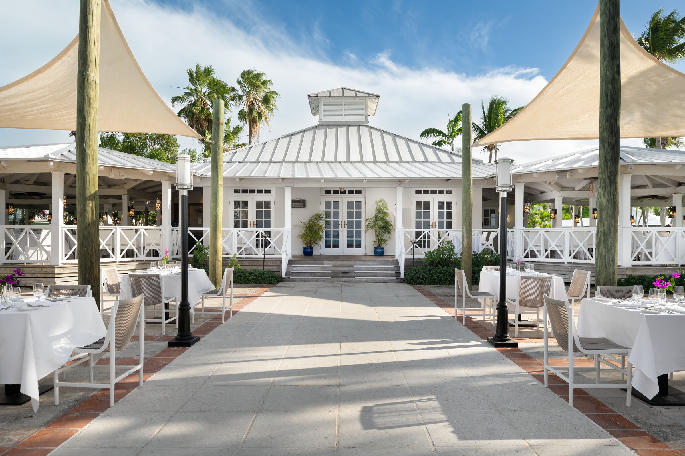 Schooners open-air restaurant with white tables under sail shades.