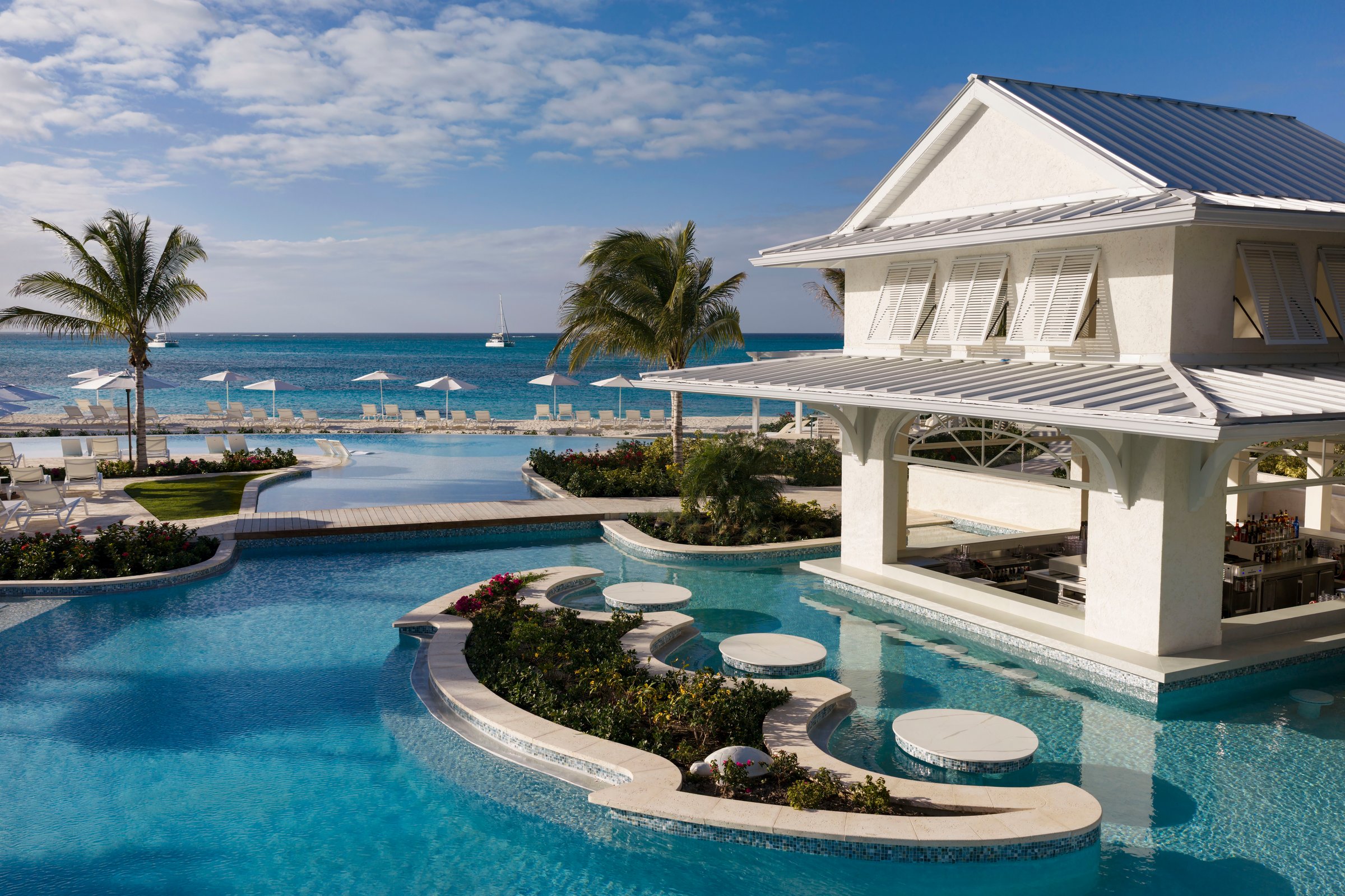 Treasure Beach infinity pool with in-water stools and a white pavilion bar.