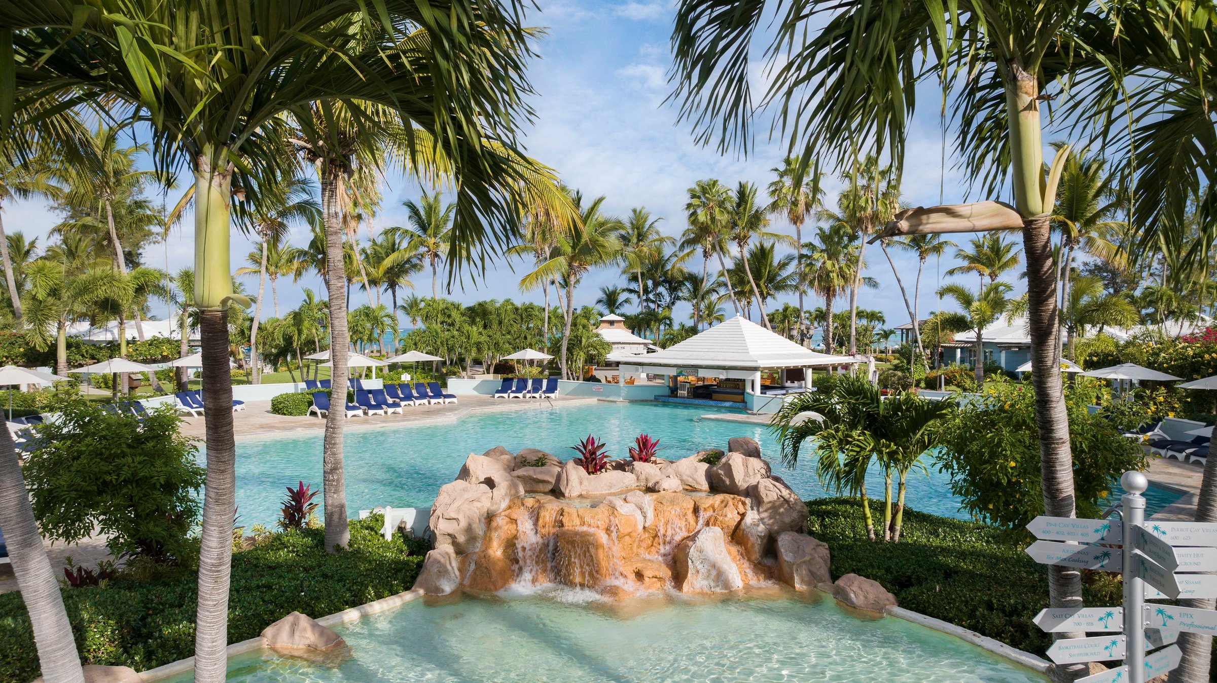 Caribbean Village pool with a rock waterfall and palms.