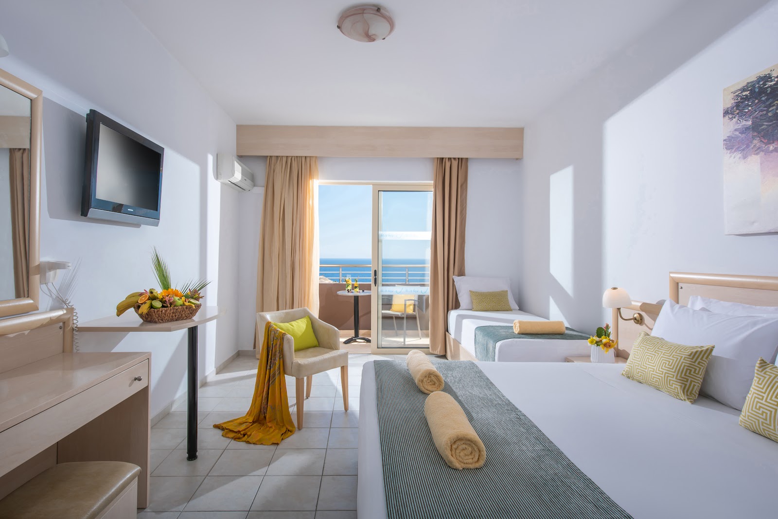 Resort room with two beds, seating area, and balcony overlooking the sea at Blue Bay Resort Hotel.