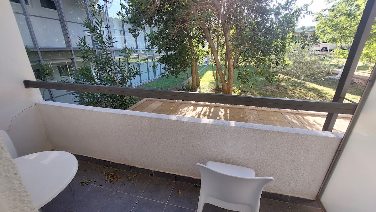 Balcony with white chairs overlooking green grounds and trees at Bluesun Hotel Neptun.