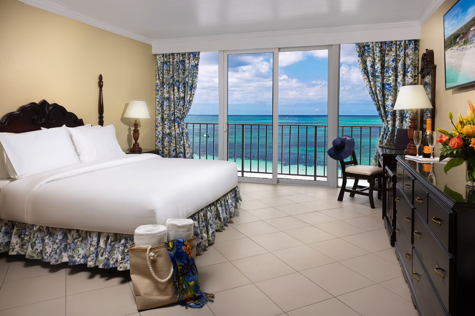 Oceanfront bedroom with king bed, glass doors opening to a balcony overlooking turquoise water at Breezes Resort Bahamas.