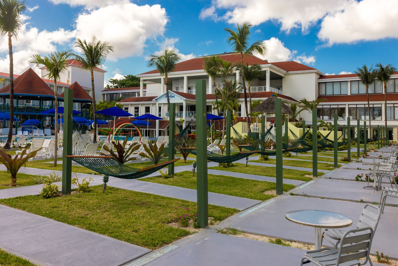 Breezes Resort Bahamas grounds with hammocks, palm trees, lounge chairs, and red-roofed white buildings under blue sky.