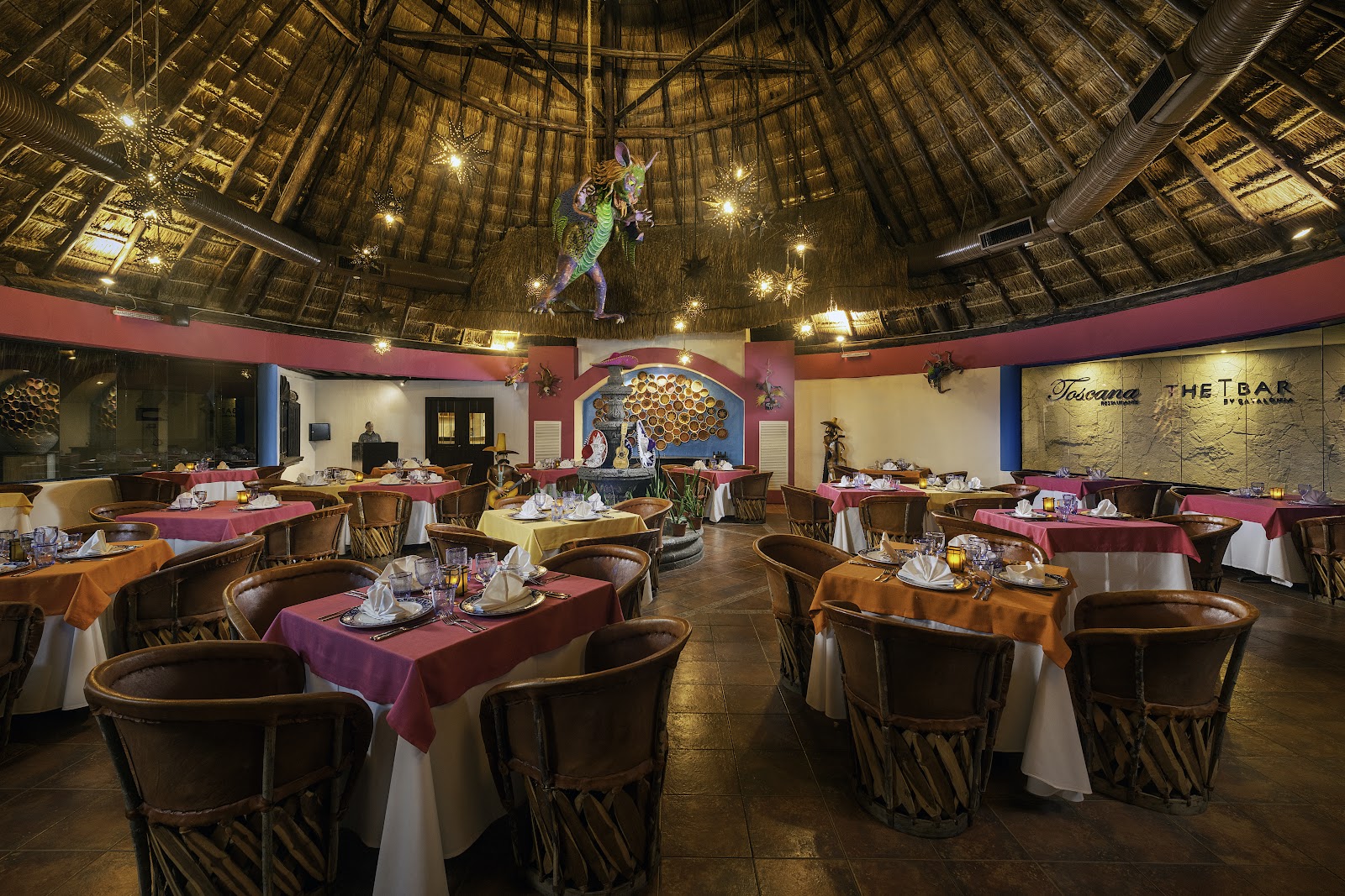 Buffet dining area at Hotel Catalonia Riviera Maya with display cases of fresh fruits, vegetables, and prepared dishes under arched ceilings.