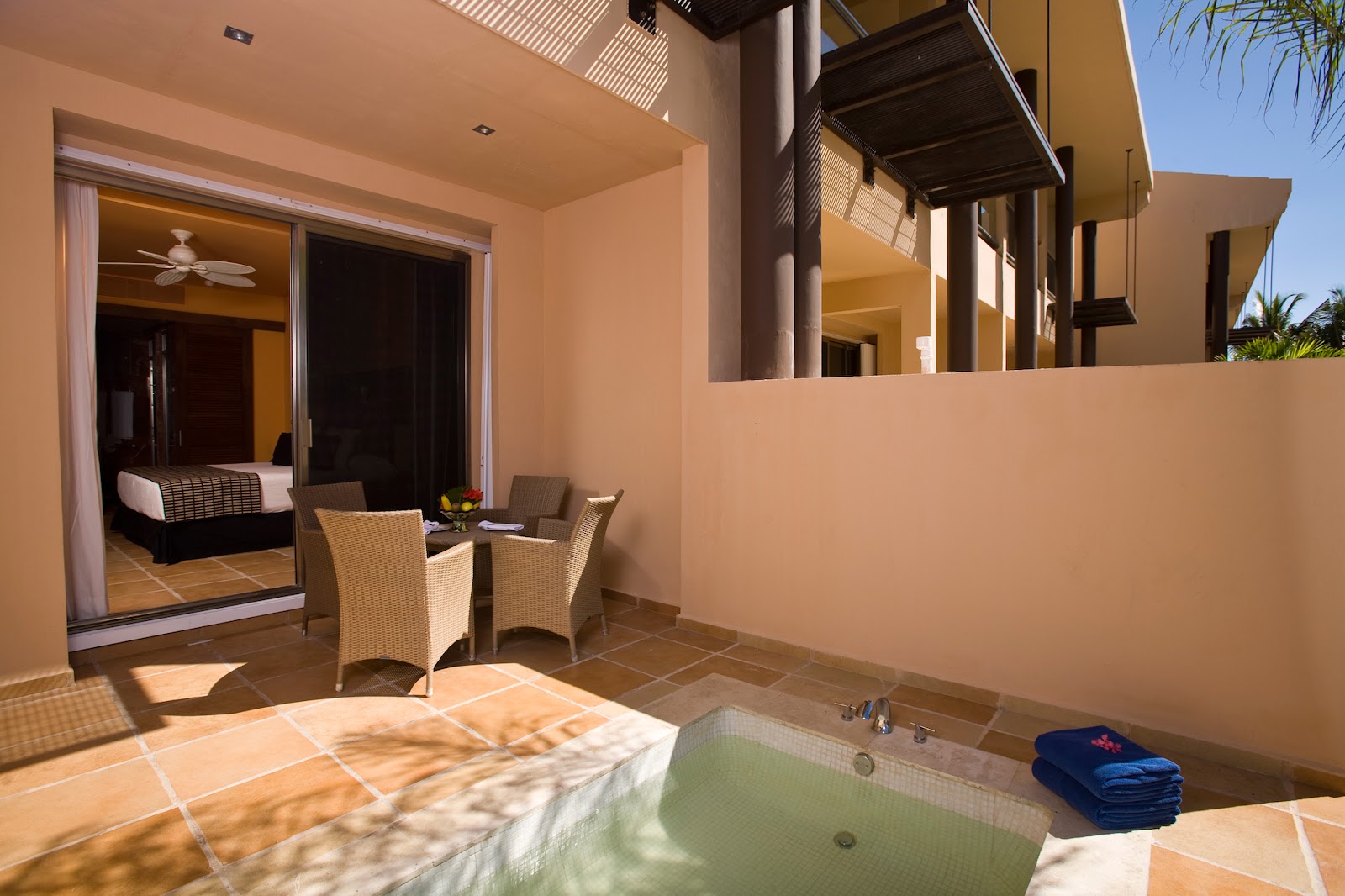 Private terrace with hot tub, wicker seating, and sliding glass doors opening to a bedroom at Hotel Catalonia Riviera Maya.