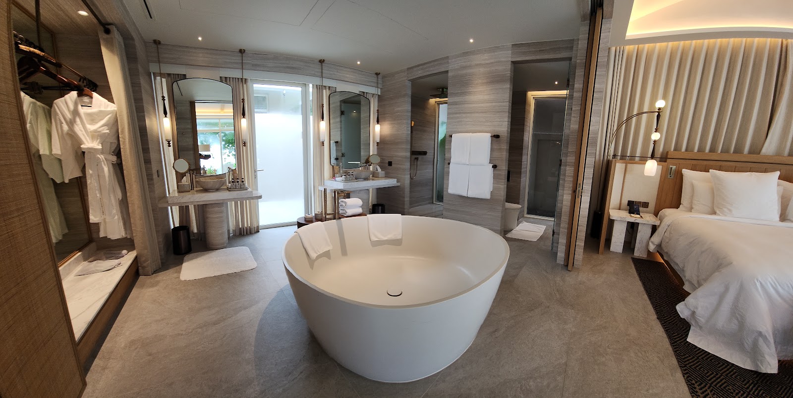 Spacious resort suite bathroom with freestanding white soaking tub, dual vanities, walk-in shower, and ocean-view balcony access at Centara Reserve Samui.