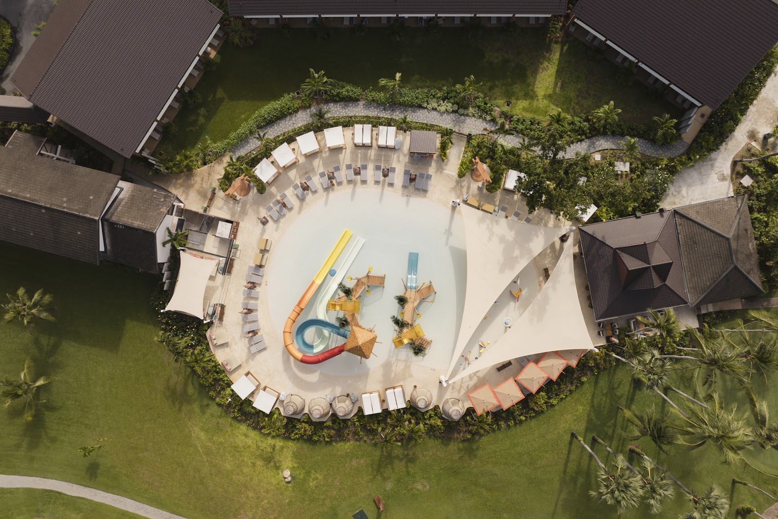 Two guests holding tennis rackets on a blue court with yellow balls scattered around at Club Med Phuket.