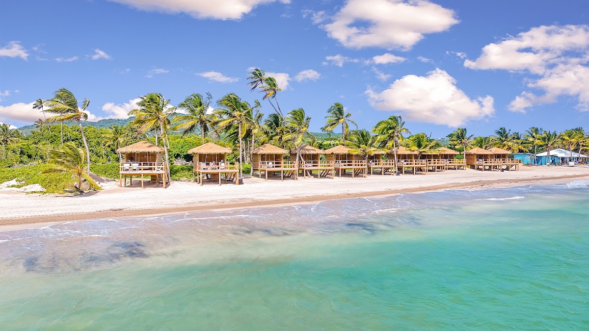 Thatched bungalows line a sandy beach with turquoise water at Coconut Bay Beach Resort & Spa, palm trees swaying in the breeze.