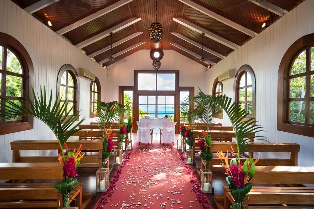 Beachfront dining setup at Conrad Bora Bora Nui with tropical fruit plates, coffee service, and overwater bungalows across turquoise lagoon.