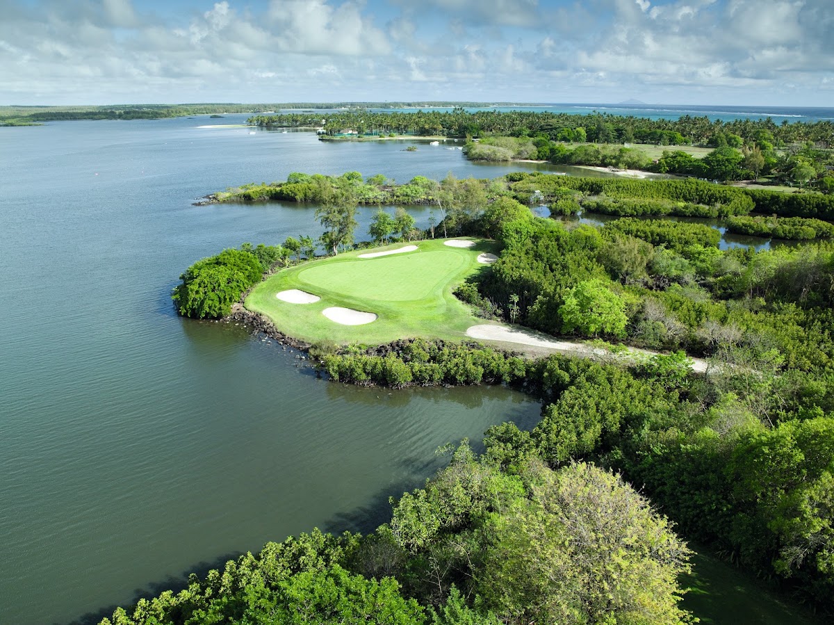 Golf course on a peninsular island surrounded by blue water and dense green mangrove vegetation at Constance Belle Mare Plage.