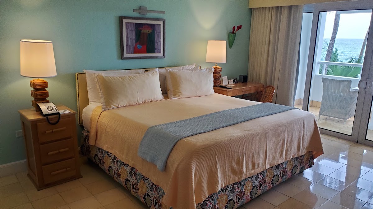 Bedroom with king bed, turquoise walls, and ocean view through sliding glass doors at Couples Tower Isle.