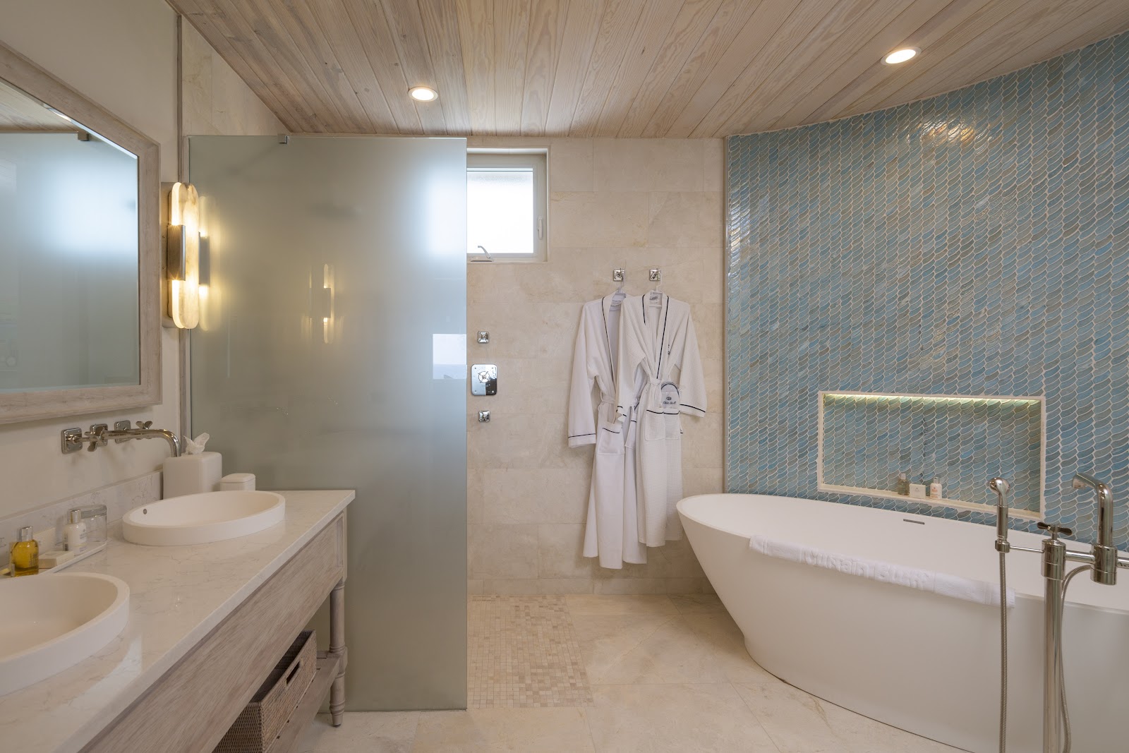 Spa-style bathroom with freestanding soaking tub, dual sinks, walk-in shower, and blue-tiled accent wall at Curtain Bluff.
