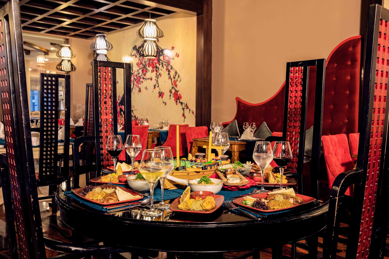 Fine dining table set with plated seafood, fried items, and vegetables alongside wine glasses and red napkins at Delphin Imperial Hotel.