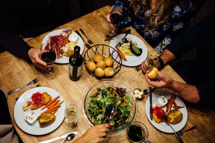Dining table set with roasted meat, potatoes, salads, and side dishes at Denali Backcountry Lodge.