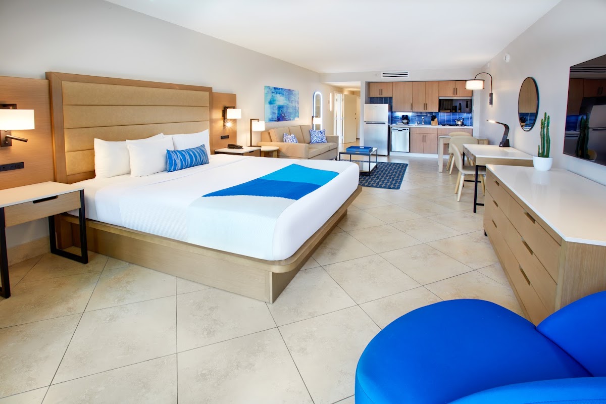 Spacious suite with king bed, blue accents, kitchenette, living area, and tile flooring at Divi Village Golf & Beach Resort.