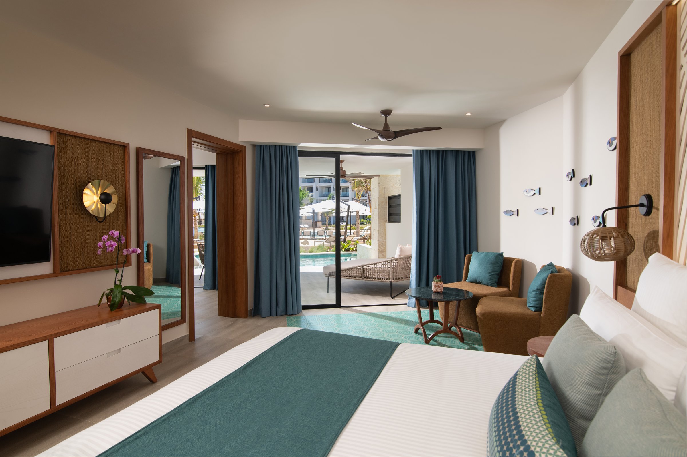 Master suite bedroom and seating area opening to a balcony overlooking the pool.