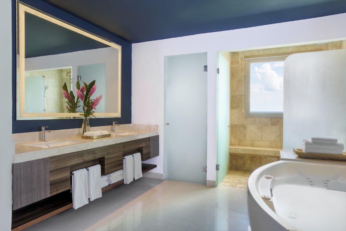 Modern bathroom with double vanity, lighted mirror, and round soaking tub at Dreams Puerto Morelos Resort & Spa.