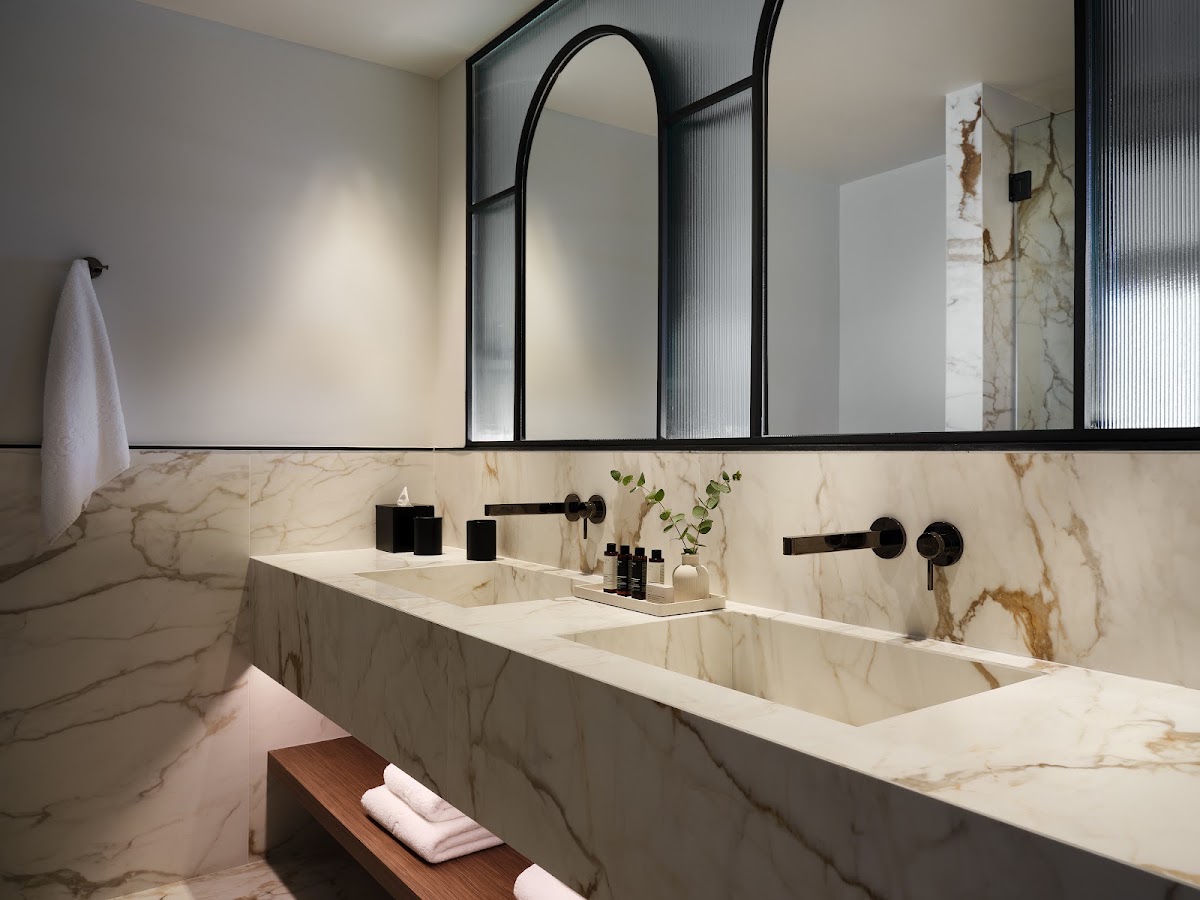 Marble bathroom with dual sinks, black framed mirror, and black fixtures at Eagles Palace resort.