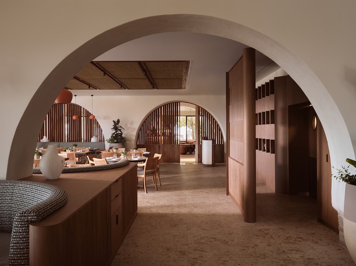 Modern dining room with curved archway, wooden lattice screens, natural light from arched windows, and tables set for service at Eagles Palace.