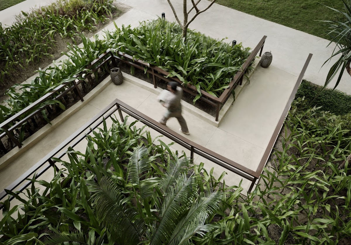 Overhead view of a guest walking across a concrete pathway bordered by lush tropical plants and raised planter beds at El Nido Resorts Lagen Island.
