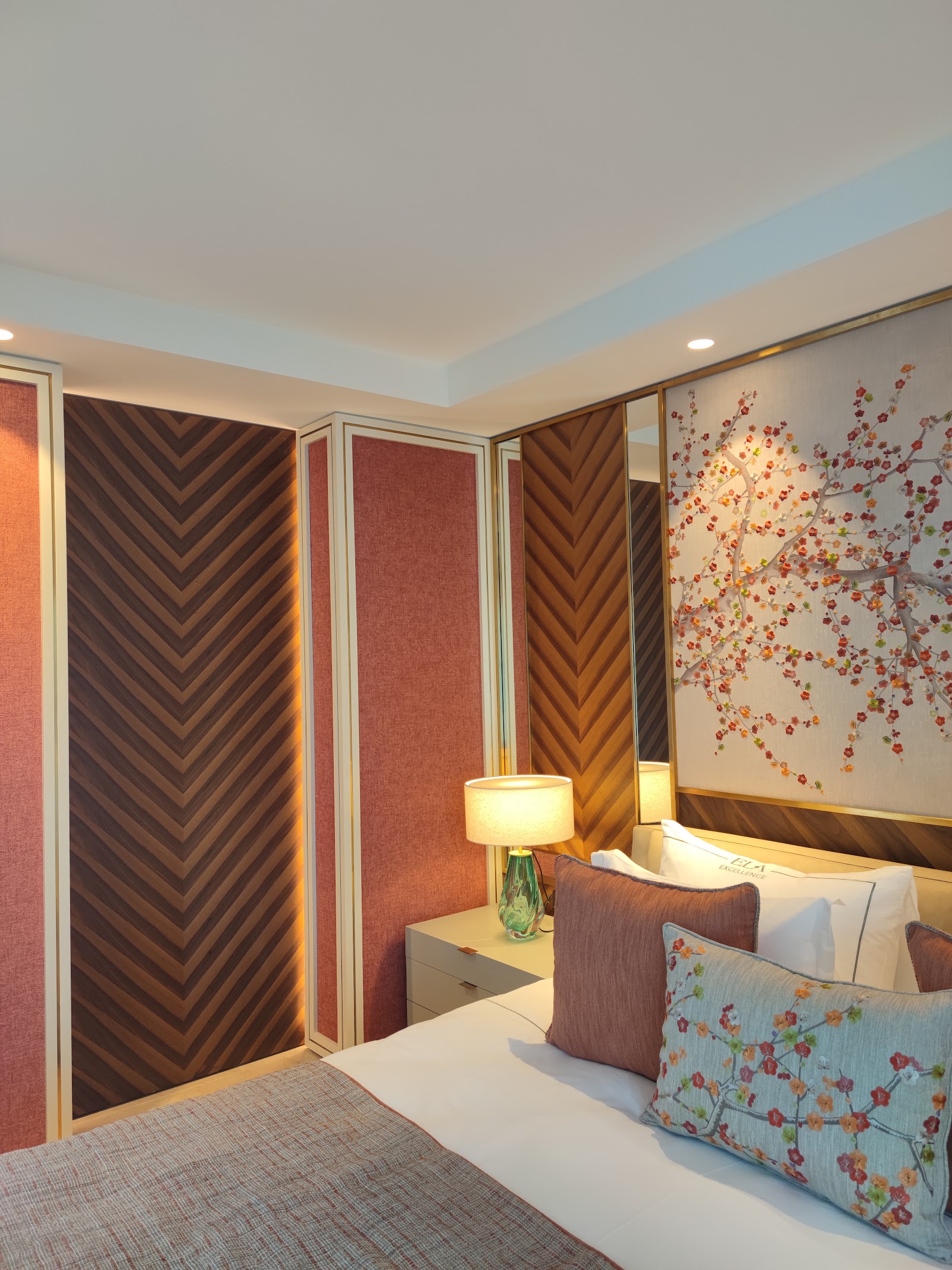 Spacious resort bedroom with two double beds, patterned bedding, and floor-to-ceiling windows with gray curtains opening to a balcony.