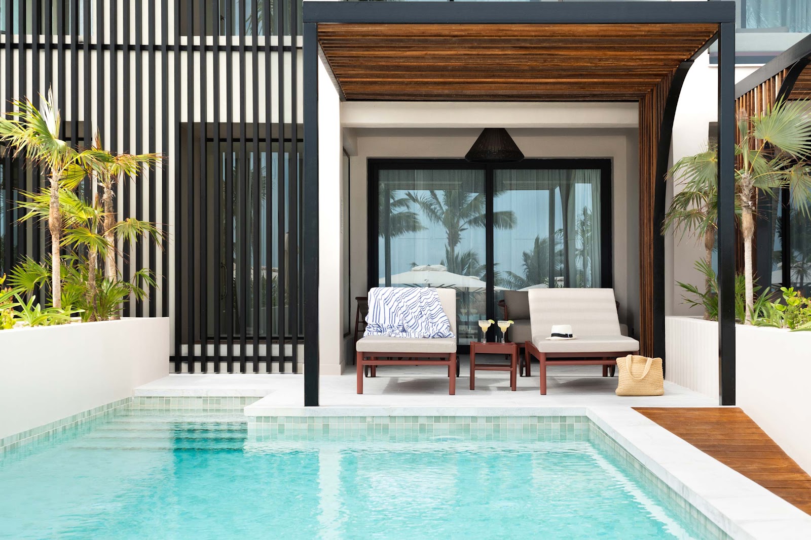 Private pool terrace with lounge chairs, pergola, and glass doors opening to a modern villa at Excellence Coral Playa Mujeres.