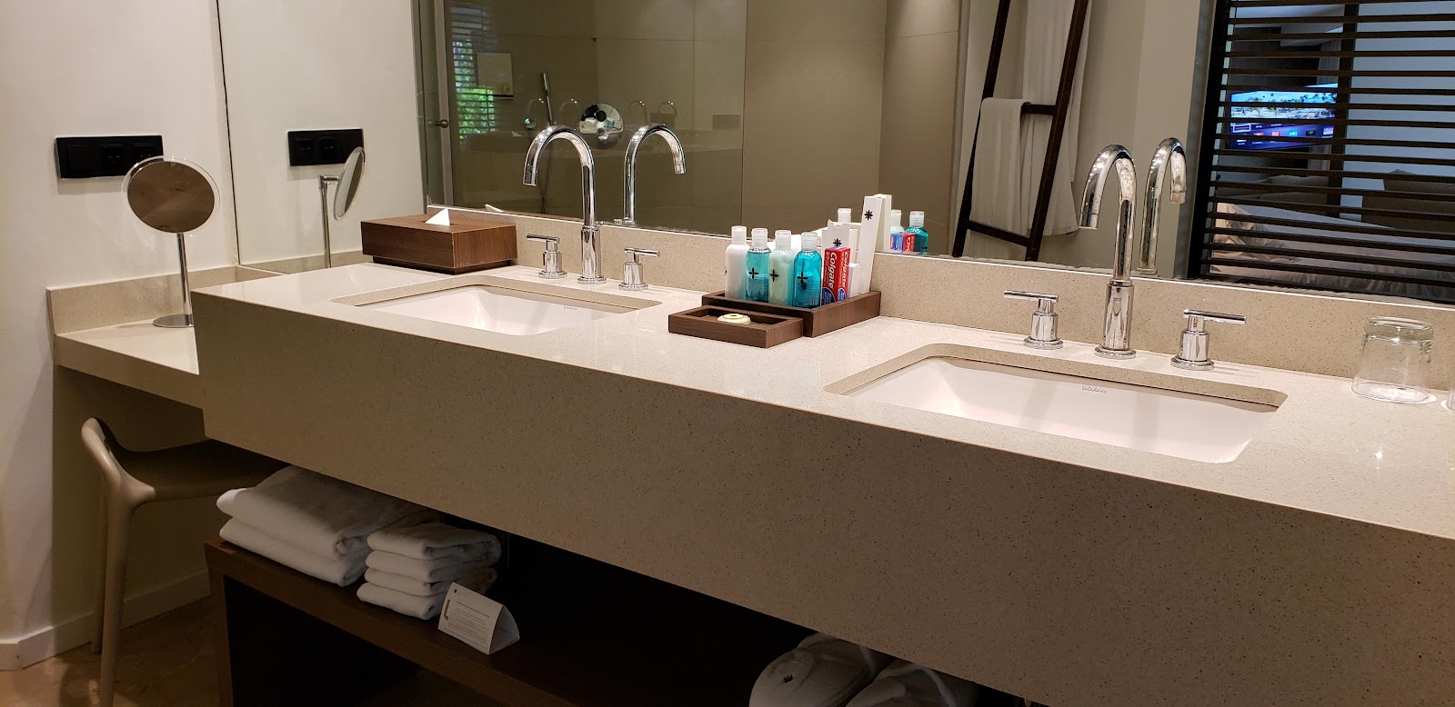 Long bathroom vanity with dual sinks, chrome faucets, amenity bottles, and folded towels at Excellence El Carmen.