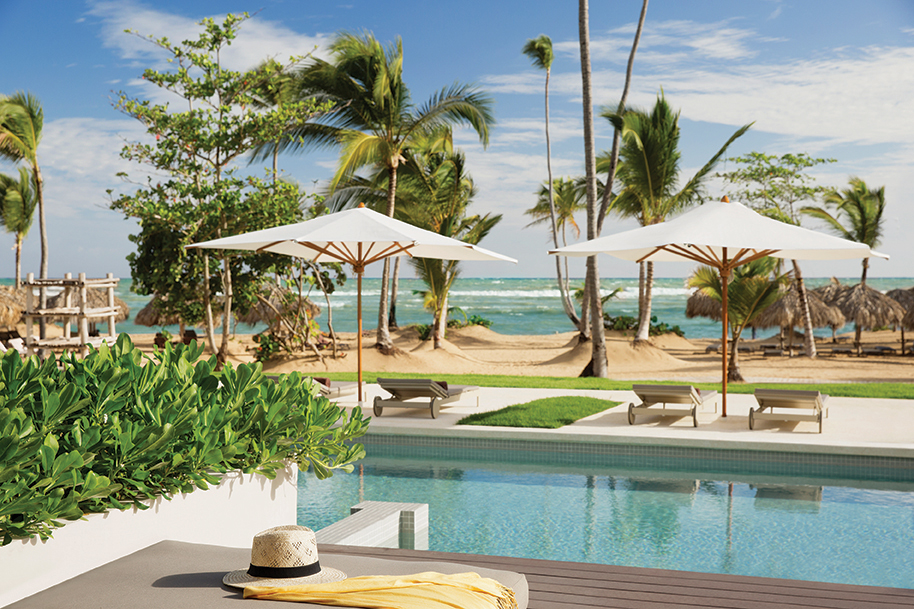 Poolside terrace with loungers and umbrellas facing the ocean at Excellence El Carmen.