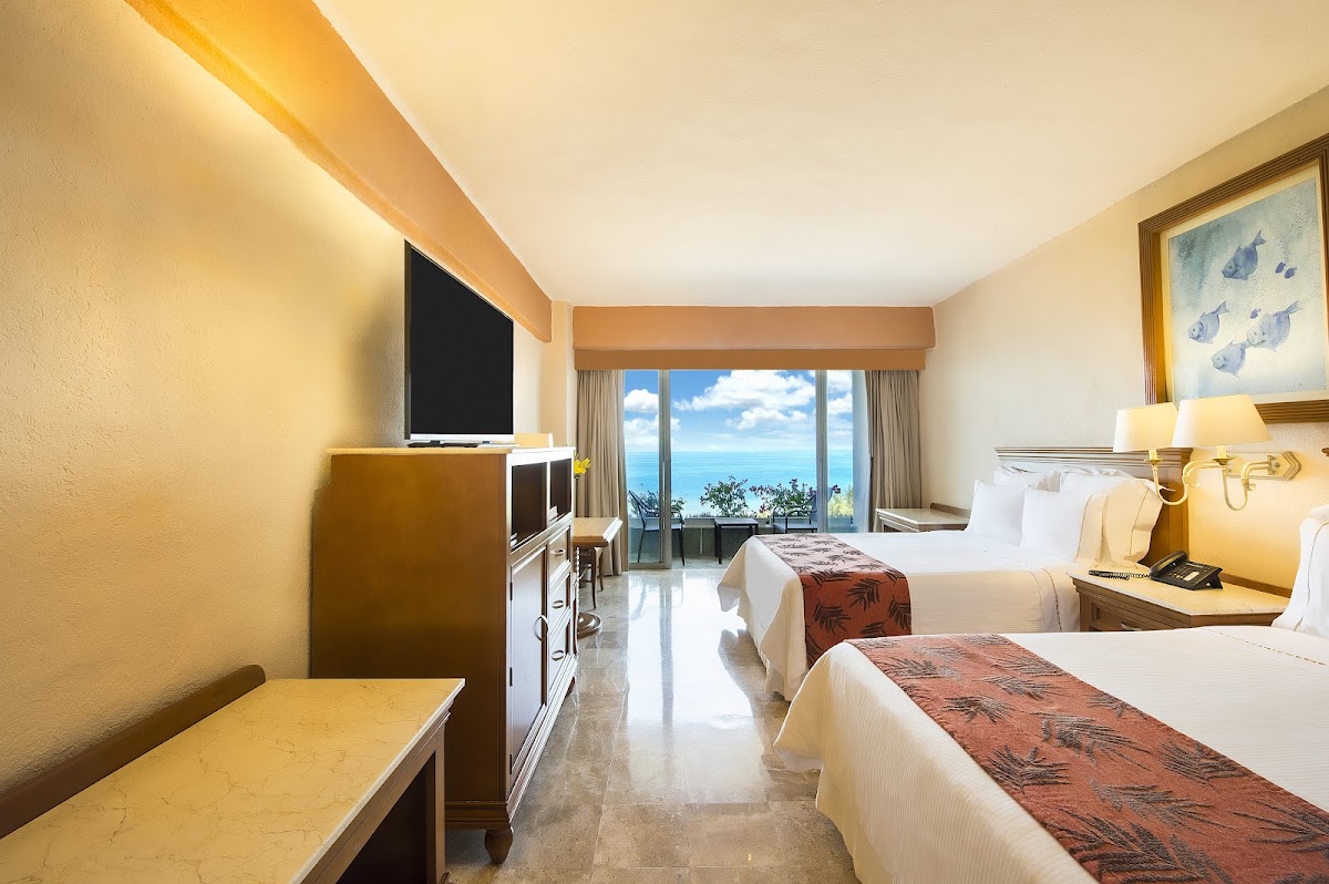 Double bed hotel room with ocean view through balcony doors at Fiesta Americana Puerto Vallarta All Inclusive & Spa.