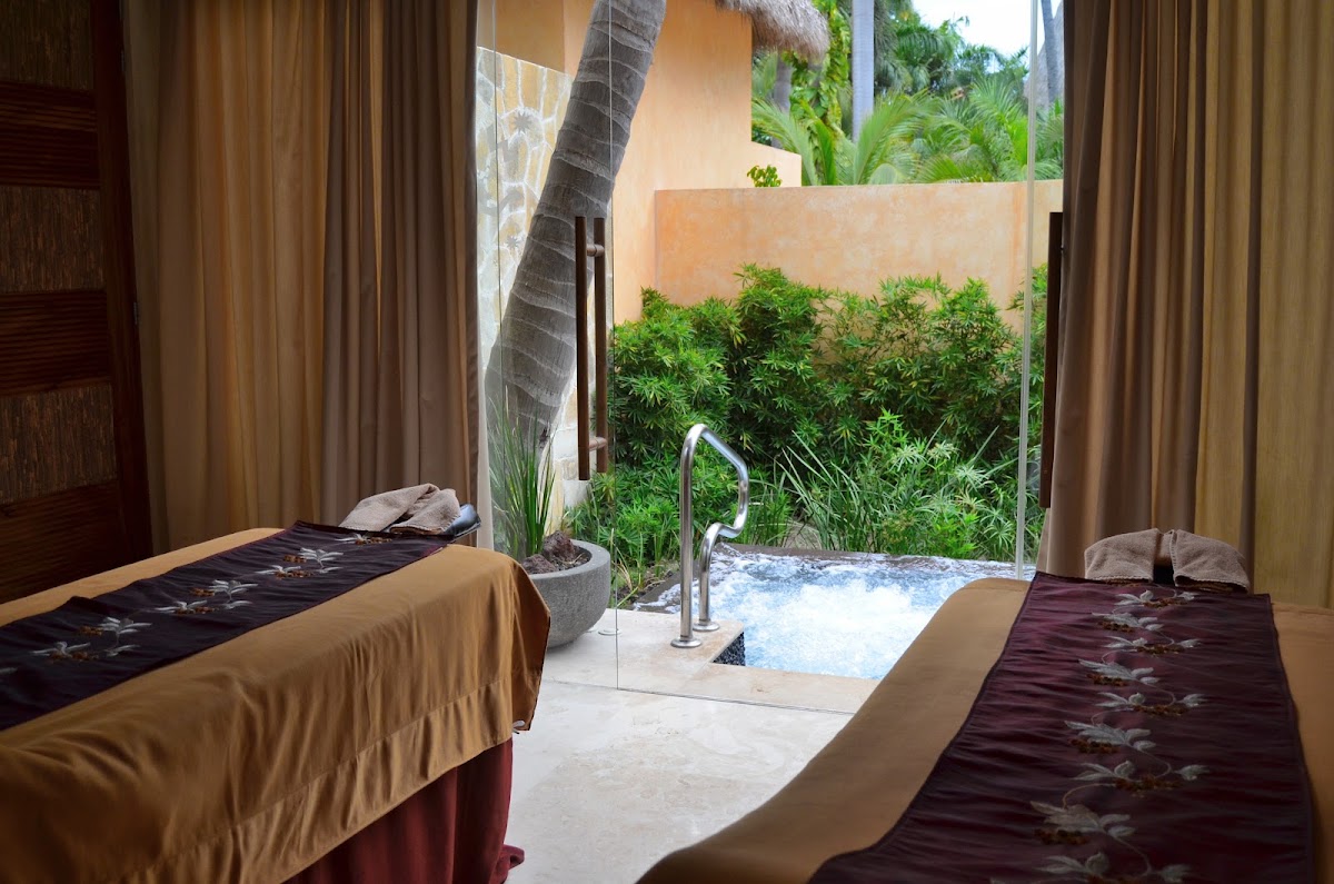 Spa treatment room with two massage beds and an outdoor soaking tub overlooking a tropical garden at Fiesta Americana Puerto Vallarta.